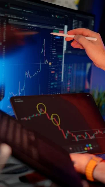 A modern workspace showing hands analyzing marketing data on a laptop and paper documents.